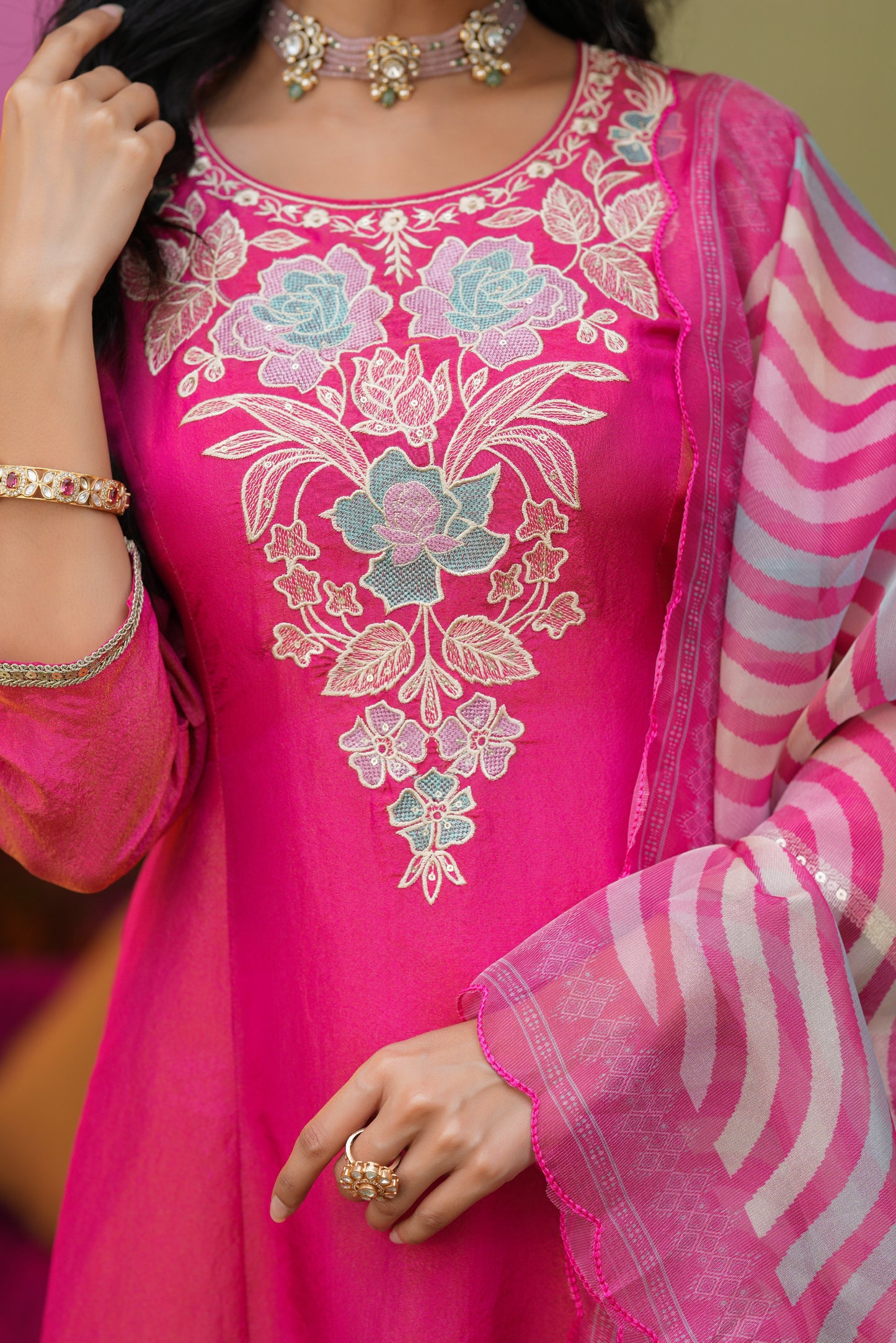 A woman in Nivishas - Sec46’s Gulabi Grace: a hot pink embroidered kurta set with blue and white floral work, paired with a striped dupatta—ideal for festive celebrations.